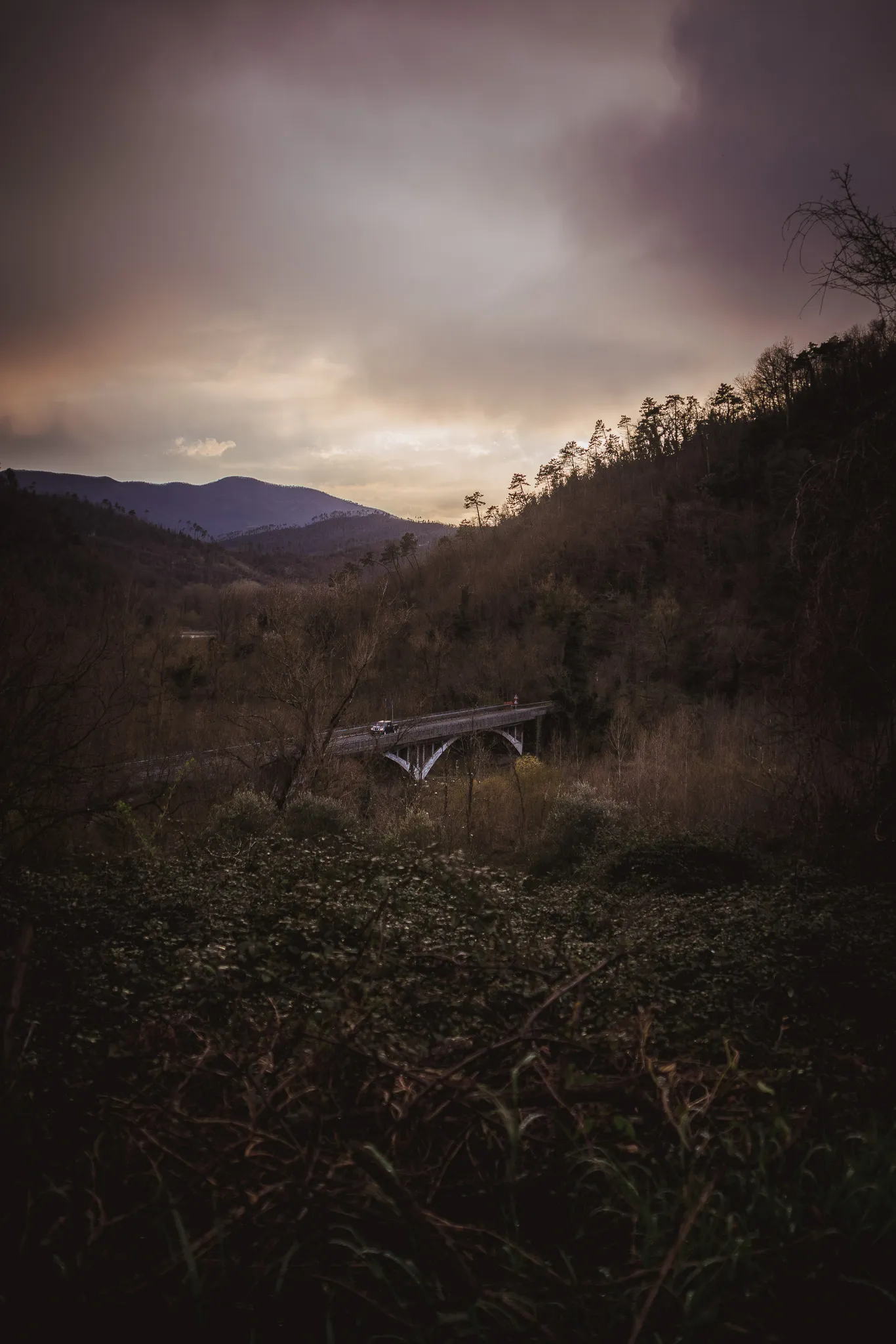 Pendio di collina con un viadotto sotto un cielo scuro di nuvole