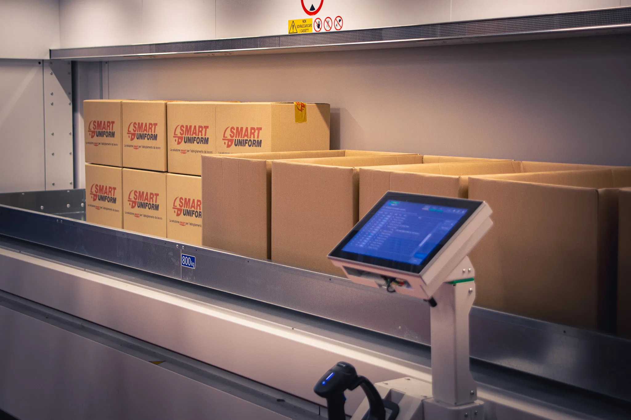 Linea di imballaggio con scatoloni marchiati e un terminale touchscreen in magazzino