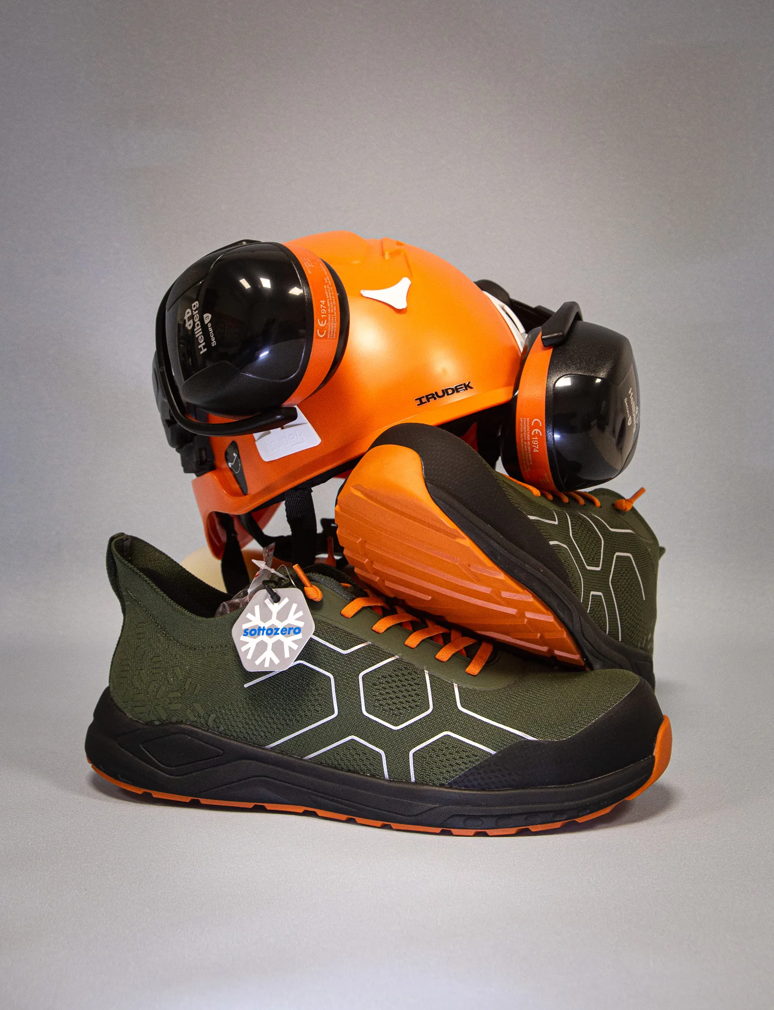 Still life di prodotto: casco da lavoro arancione con cuffie e scarpe antinfortunistiche