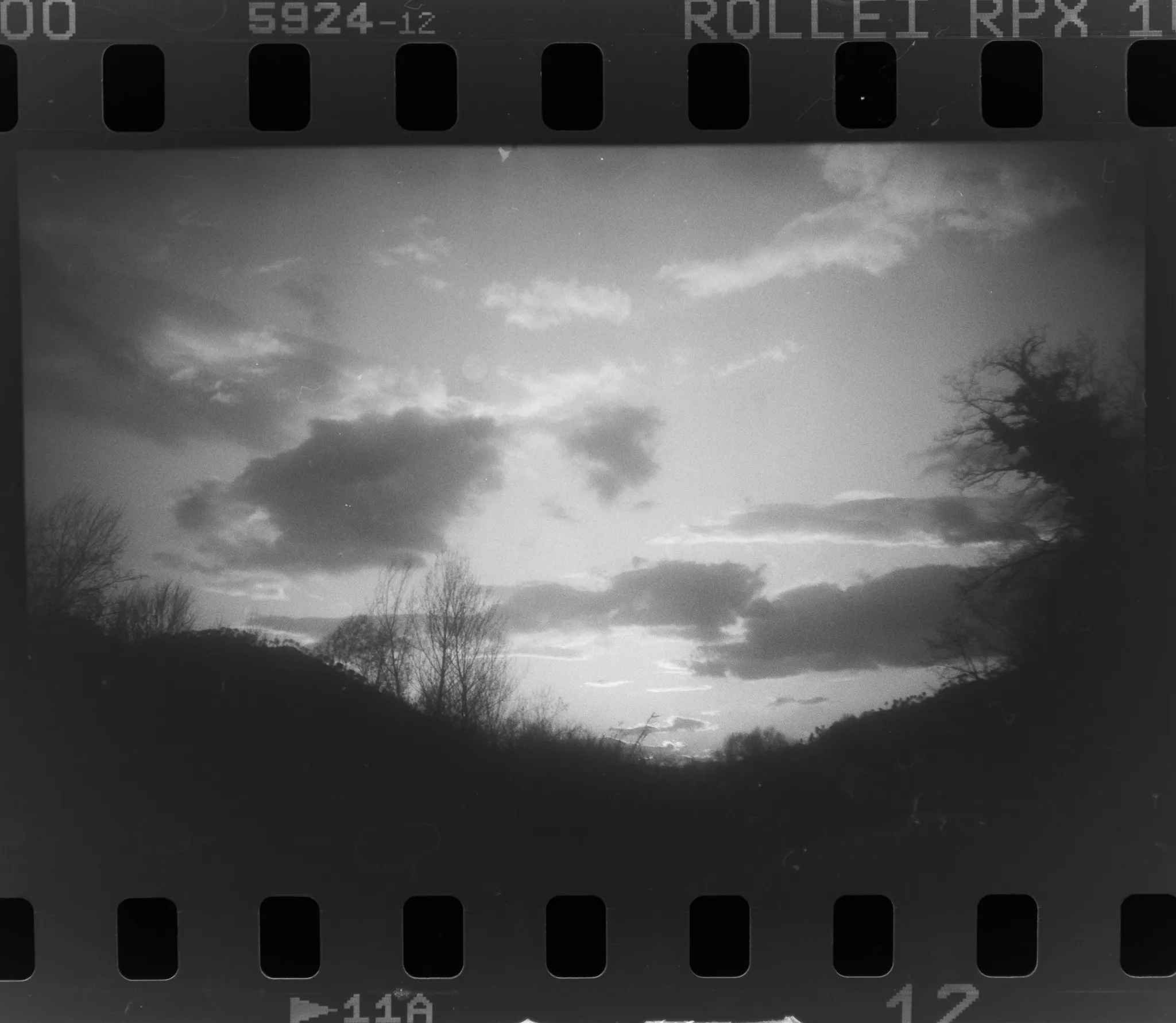 Cielo con nuvole sopra il profilo delle colline, su pellicola in bianco e nero con i bordi del negativo